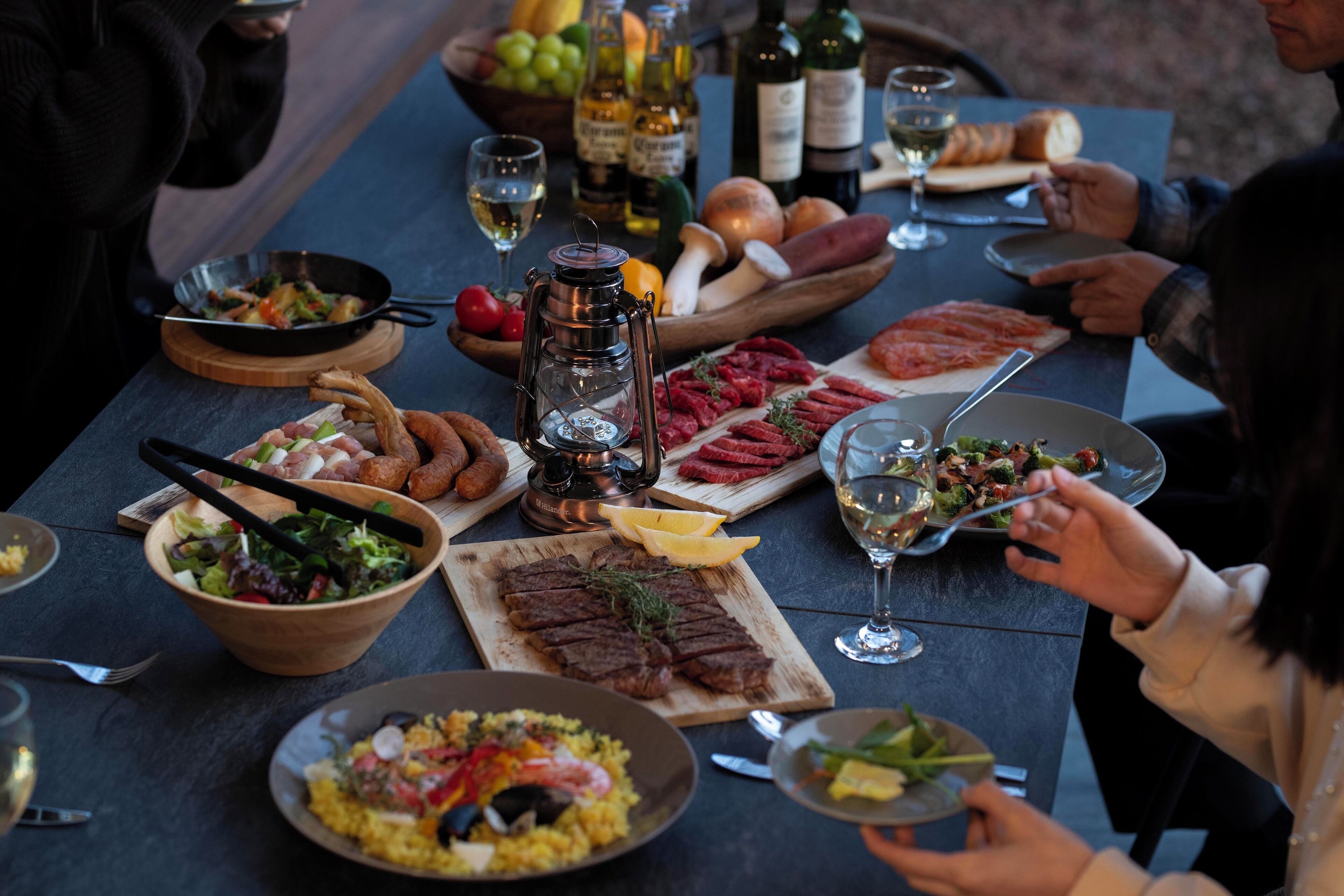 A dining table set with various dishes, including meats, salads, and bread, with wine bottles and glasses.
