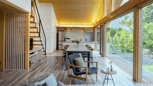 A modern interior with a wooden dining table, chairs, and a staircase leading to an upper level.