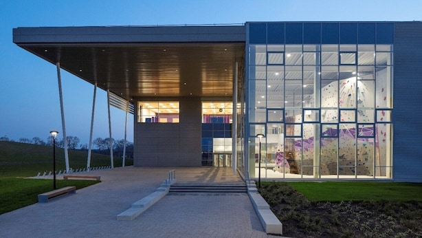 A modern building with a glass facade, a covered entrance, and a paved walkway leading to the entrance. - Warwick Conferences - Central Campus Venues  (Coventry)