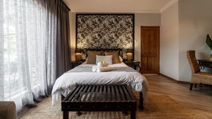 Une chambre à coucher comprenant un lit, un banc en bois, une chaise, un panneau décoratif mural et une porte.