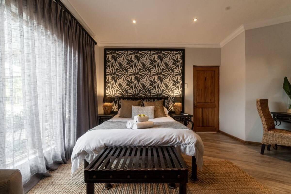 Ein Schlafzimmer mit einem Bett, einer hölzernen Bank, einem Stuhl, einer Wandverkleidung und einer Tür.