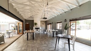 Un vaste espace dédié à la salle à manger, avec un parquet à motifs en chevrons, des chaises blanches et une table centrale.
