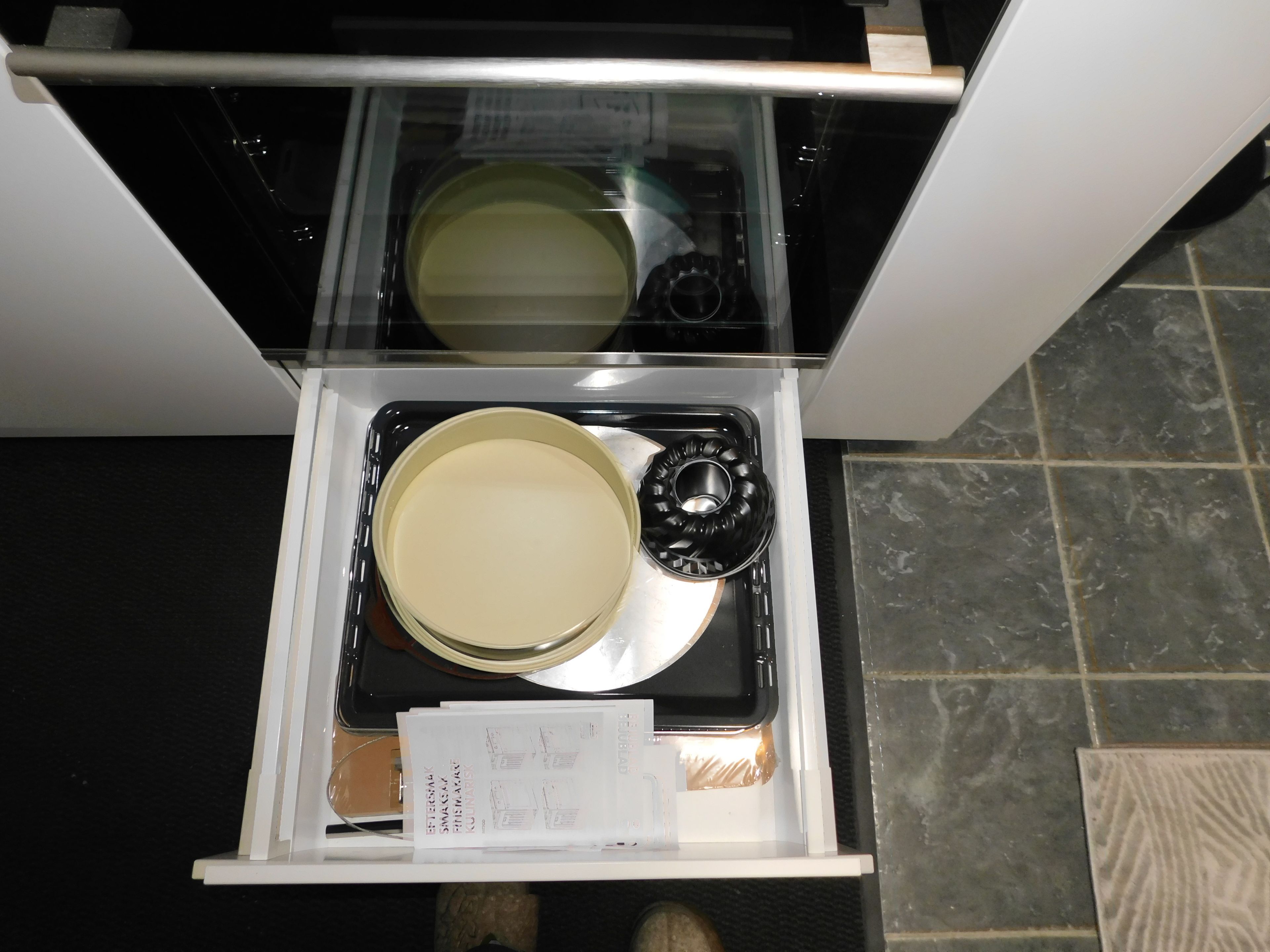 A kitchen drawer with a stove, a pot, and a pan.