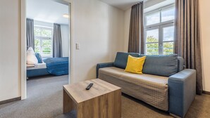 Una habitación moderna con sofá, una mesita de madera y vistas a un balcón.