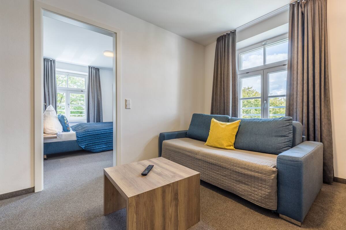Una habitación moderna con sofá, una mesita de madera y vistas a un balcón.