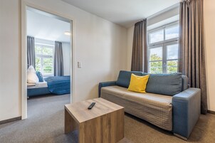 Una habitación moderna con sofá, una mesita de madera y vistas a un balcón.