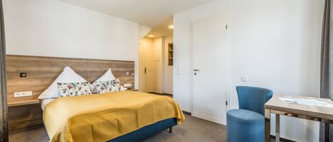 Una habitación de hotel con cama, escritorio, silla y armario.