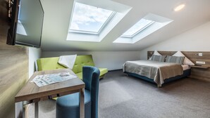 Un dormitorio moderno con tragaluces, una cama, un sofá y una mesa.