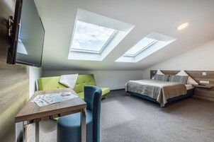 Um quarto moderno com clarabóias, uma cama, um sofá e uma mesa.
