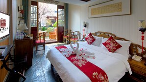 A hotel room with a large bed, a desk with a lamp, a chair, and a view of the outside.