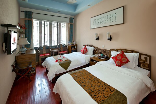 A hotel room with two beds, a desk, a chair, and a television.