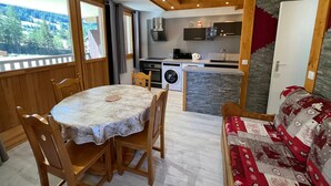 A cozy interior with a dining area, a kitchen, and a sofa. - Charming Apartment in Val-Cenis: Ski-In/Ski-Out, Terrace, 4 Guests, Renovated (Lanslevillard)
