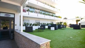 Un bâtiment moderne doté d’un toit plat, d’un espace extérieur aménagé avec du mobilier noir et d’une pelouse bien entretenue.