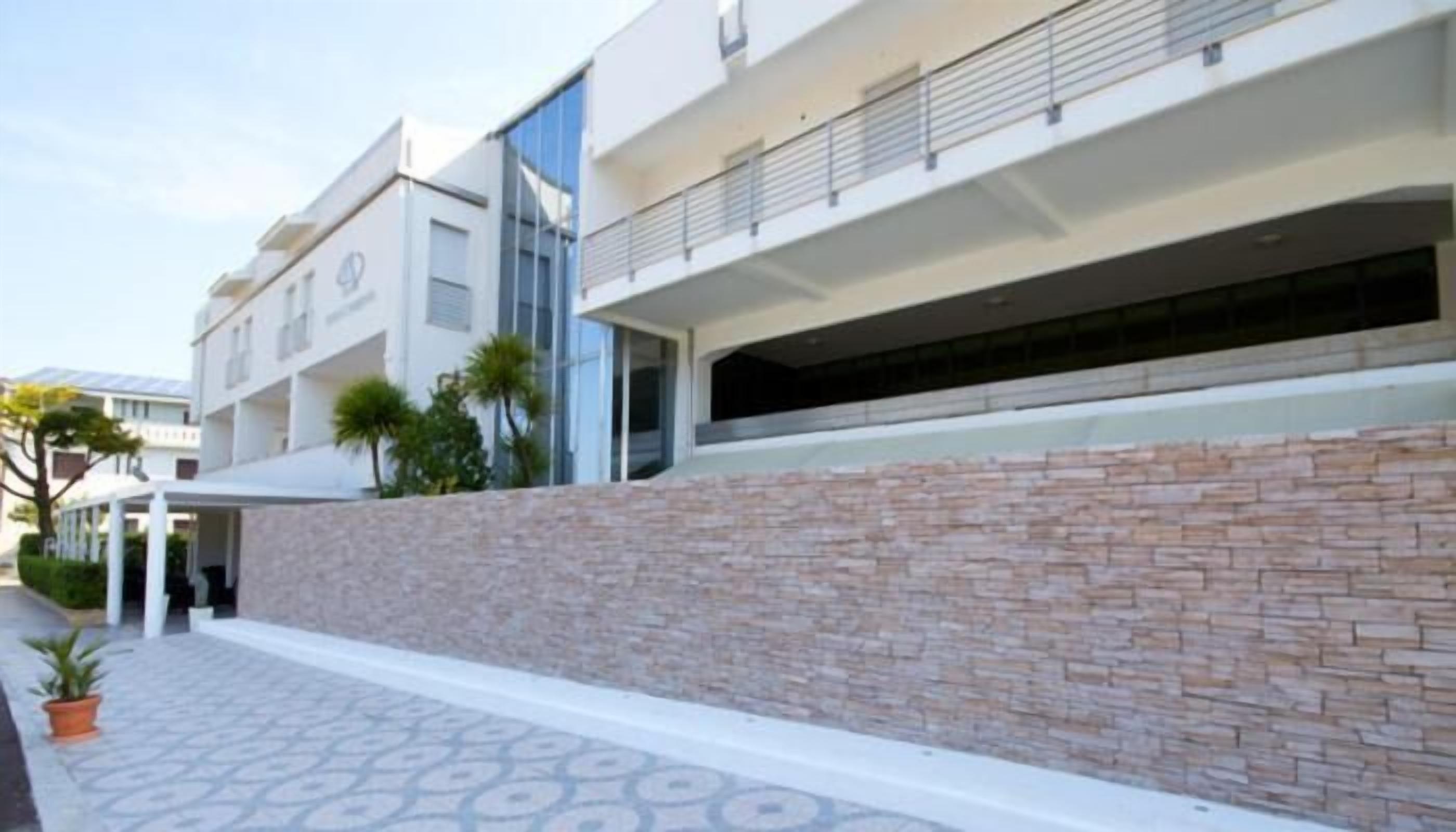 A modern building with a stone facade, a covered entrance, and a patterned walkway.