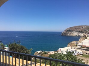 A coastal view with a balcony overlooking the sea, a rocky cliff, and buildings along the coastline. - Casa Assunta (Serrara Fontana)