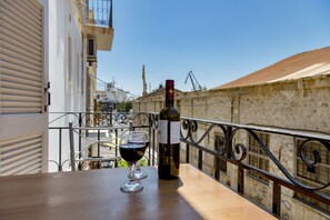 A balcony with a table, two wine glasses, and a bottle of wine. - Ethrion plus Home experience (Syros)