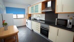 Een moderne keuken met een wasmachine, oven, magnetron en een eethoek met een tafel en stoel.