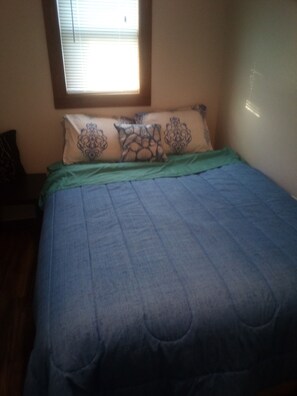 A bedroom with a bed, pillows, and a window.