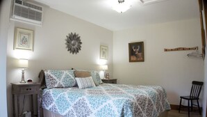 A bedroom with a bed, two bedside tables with lamps, a chair, and wall decorations.