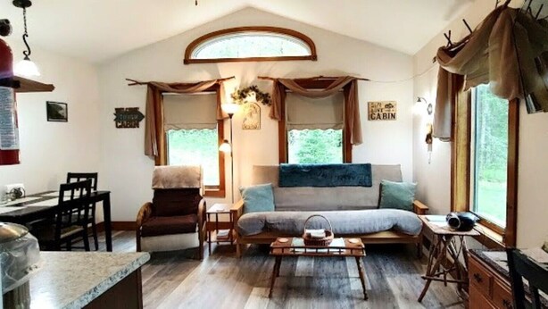 A cozy cabin-style room with a bed, a dining table, and a small kitchen area.
