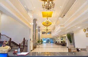 A spacious lobby with a grand chandelier, a staircase, and a reception desk. - Pursat Riverside Hotel and Spa (Sampov Meas)