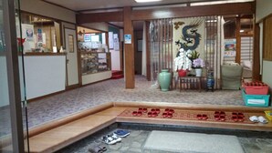 A traditional Japanese interior with tatami flooring, a shoji screen, and a display of shoes. - Daishin Ryokan (Choshi)