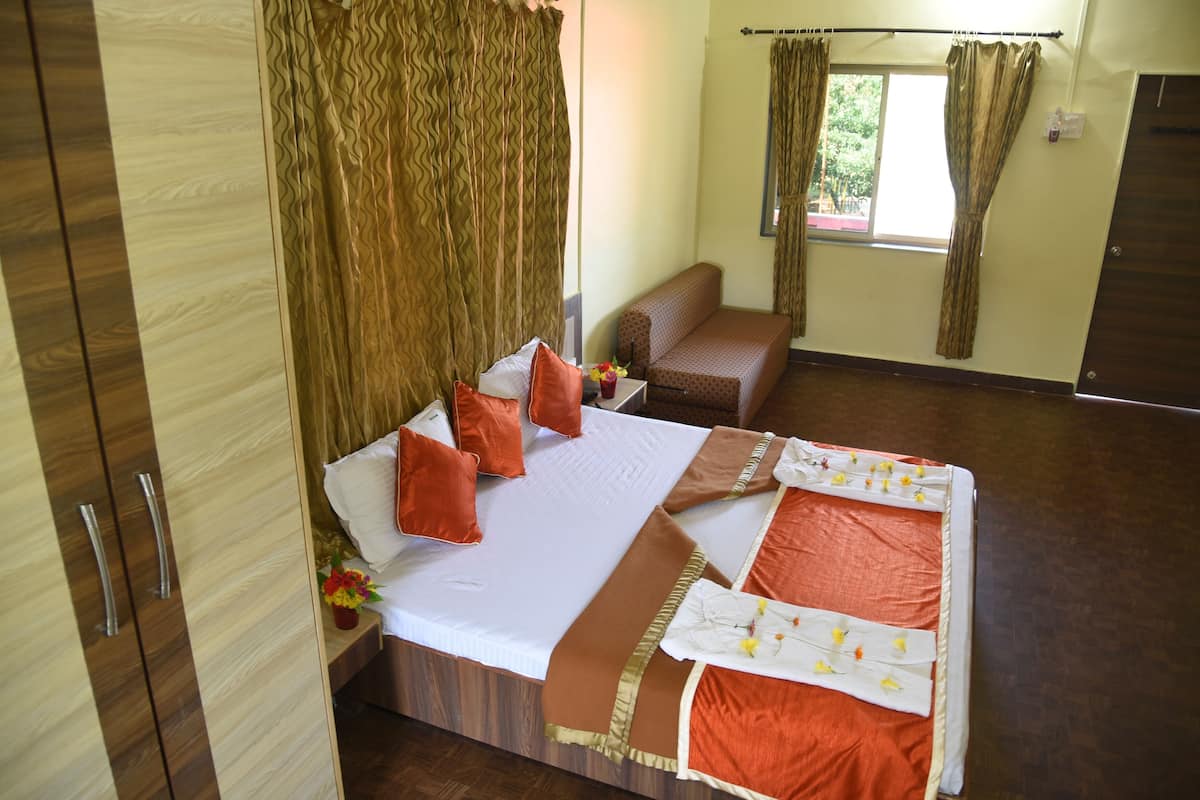 A neatly arranged hotel room with a bed, a sofa, and a window with curtains.