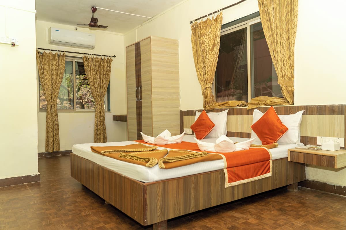 A hotel room with a wooden bed, a window with curtains, a bedside table, and an air conditioning unit.