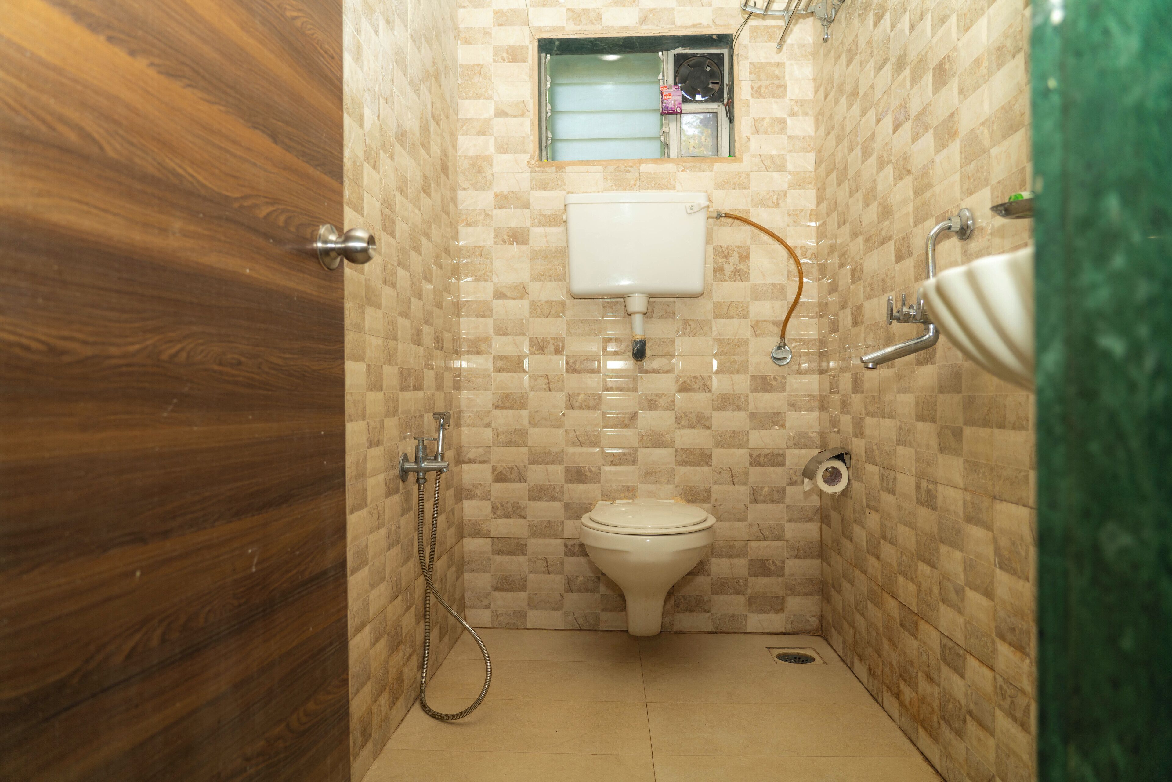 A small, tiled bathroom with a toilet, a shower, and a sink.