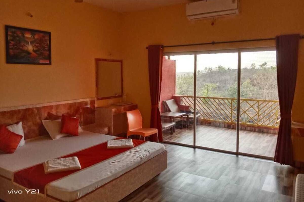 A hotel room with a bed, a desk, a chair, and a balcony with a view.