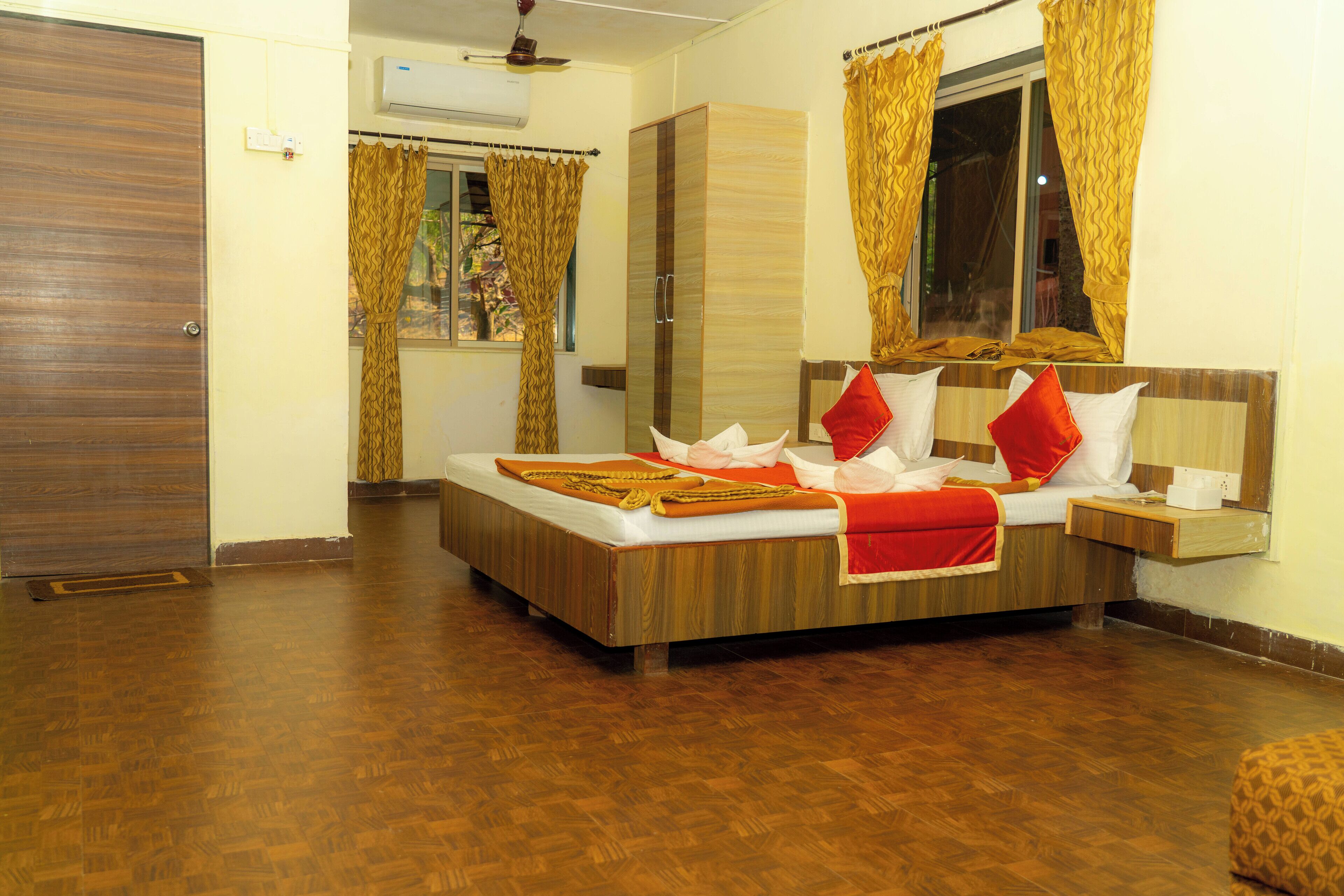 A hotel room with a wooden bed, a wardrobe, a bedside table, and a window with curtains.