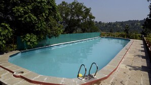 Une piscine dotée d’une plage en pierre et de garde-corps métalliques.