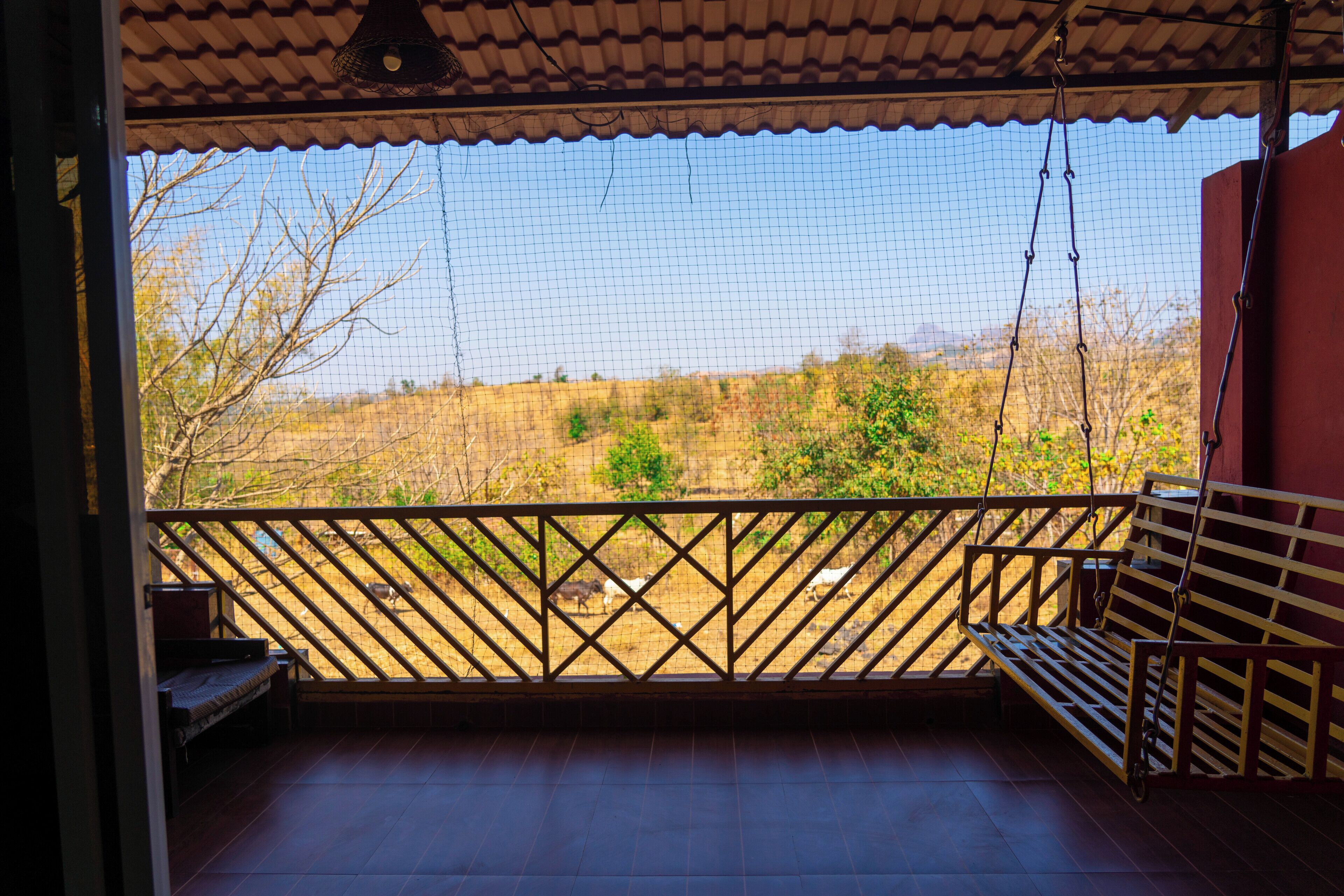 A balcony with a wooden lattice railing, a bench, and a hanging light fixture.