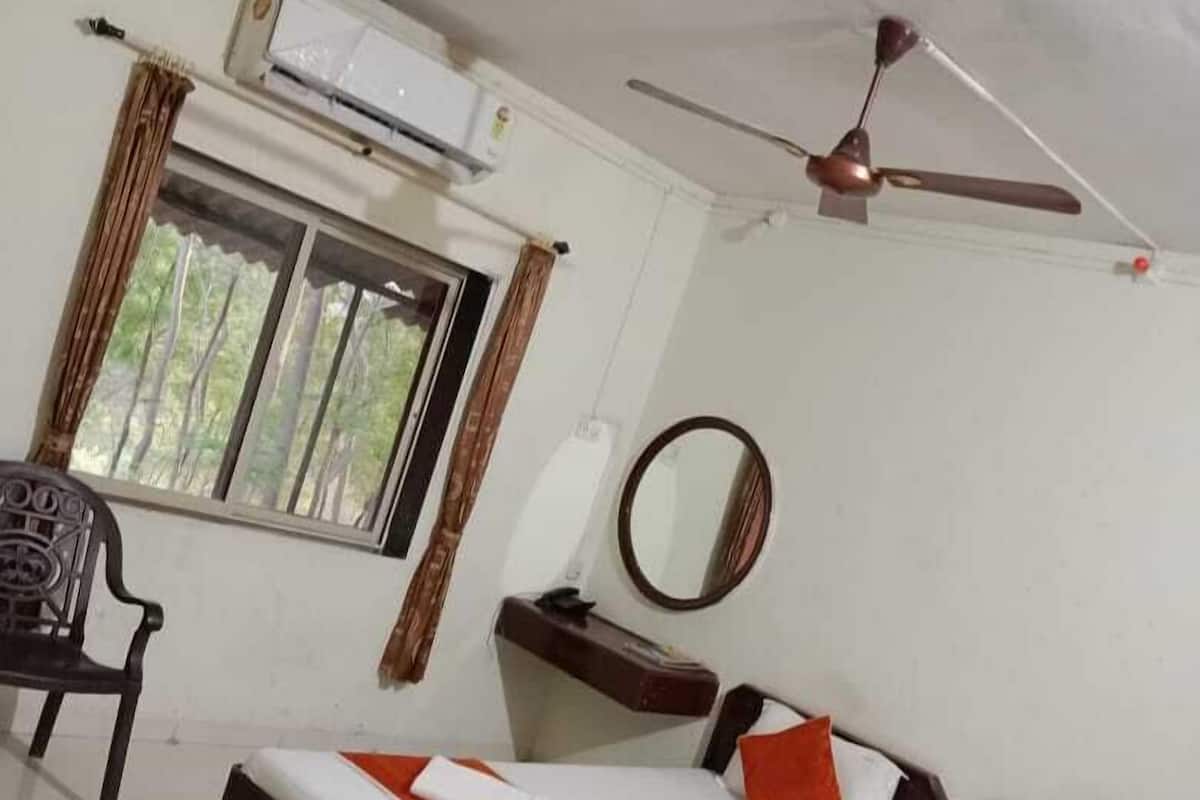 A room with a bed, a chair, a desk, a mirror, and a ceiling fan.