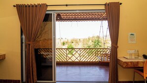 Une pièce dotée d’une porte-fenêtre coulissante donnant sur un balcon avec vue sur la verdure et une clôture en bois.