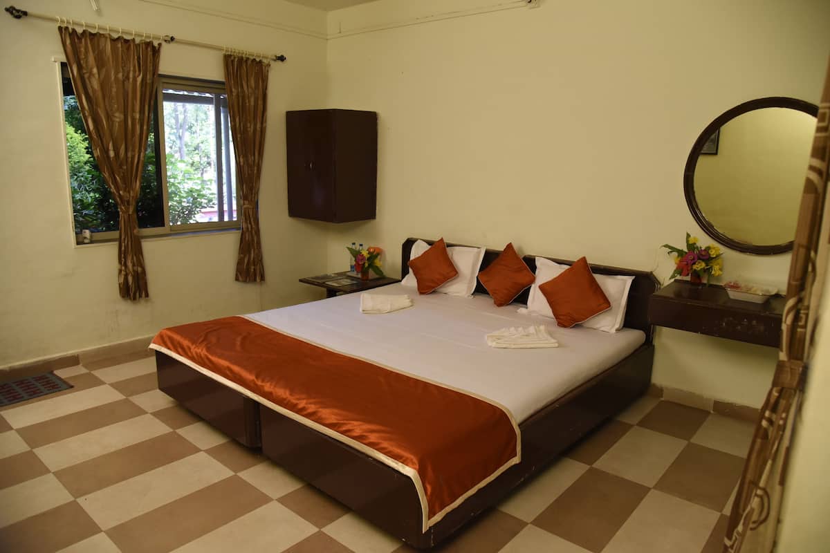 A hotel room with a large bed, a wardrobe, a bedside table with a mirror, and a window with curtains.