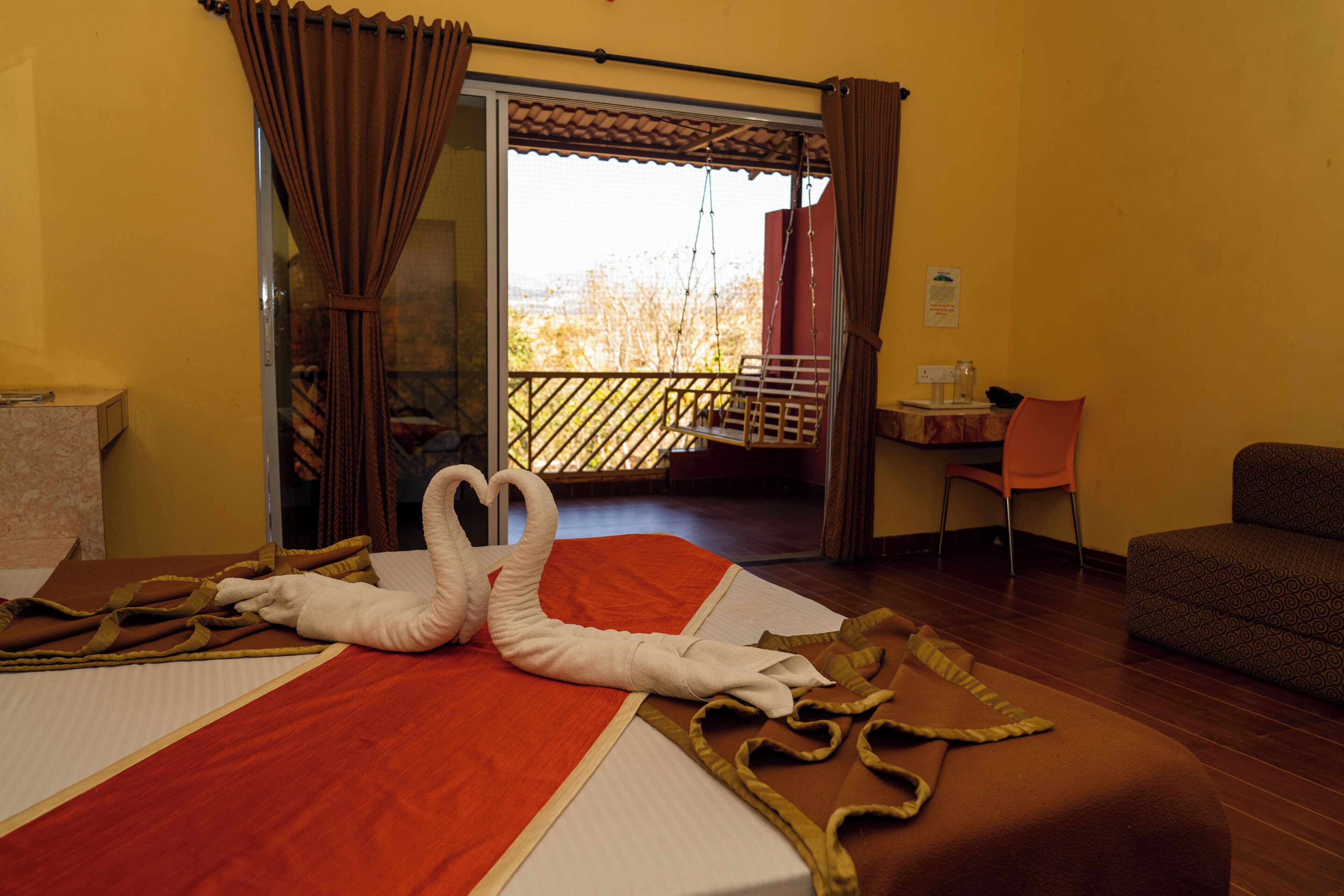A hotel room with a bed, a balcony, a chair, and a small table.
