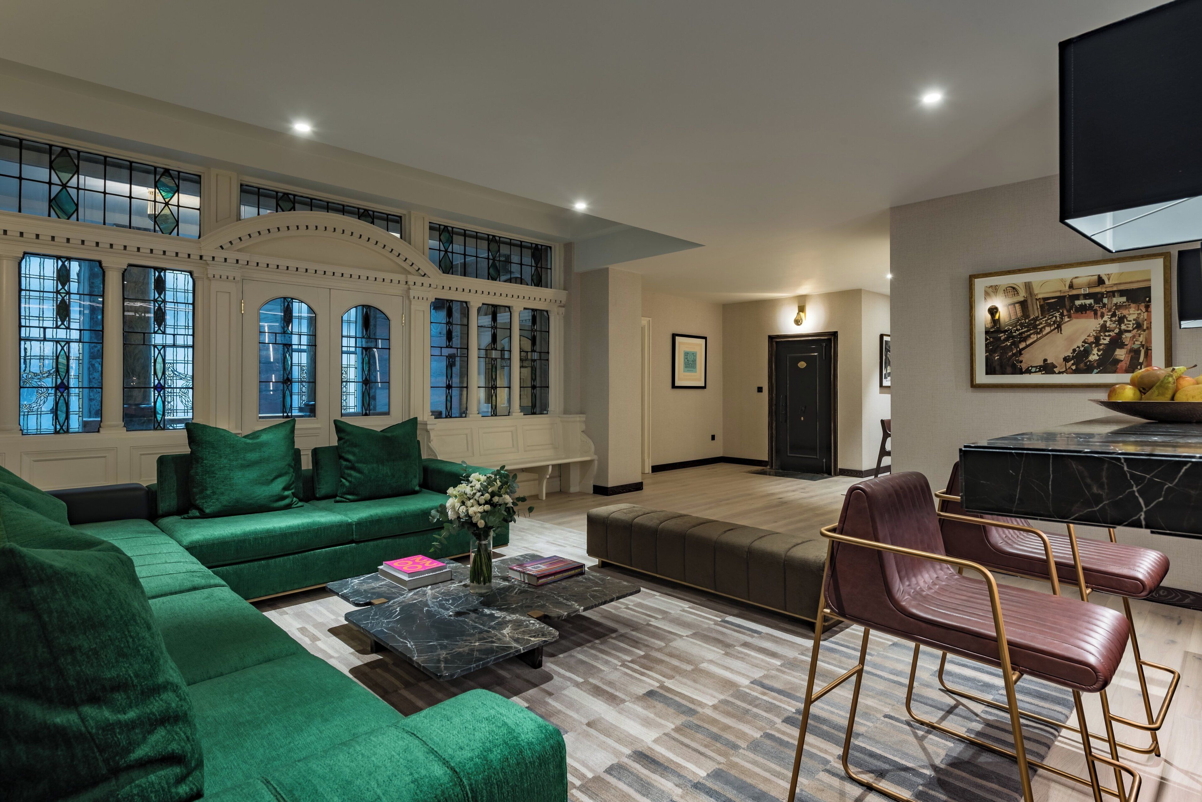 A spacious living room with a green sofa, a coffee table, and a dining area with a marble table and chairs.