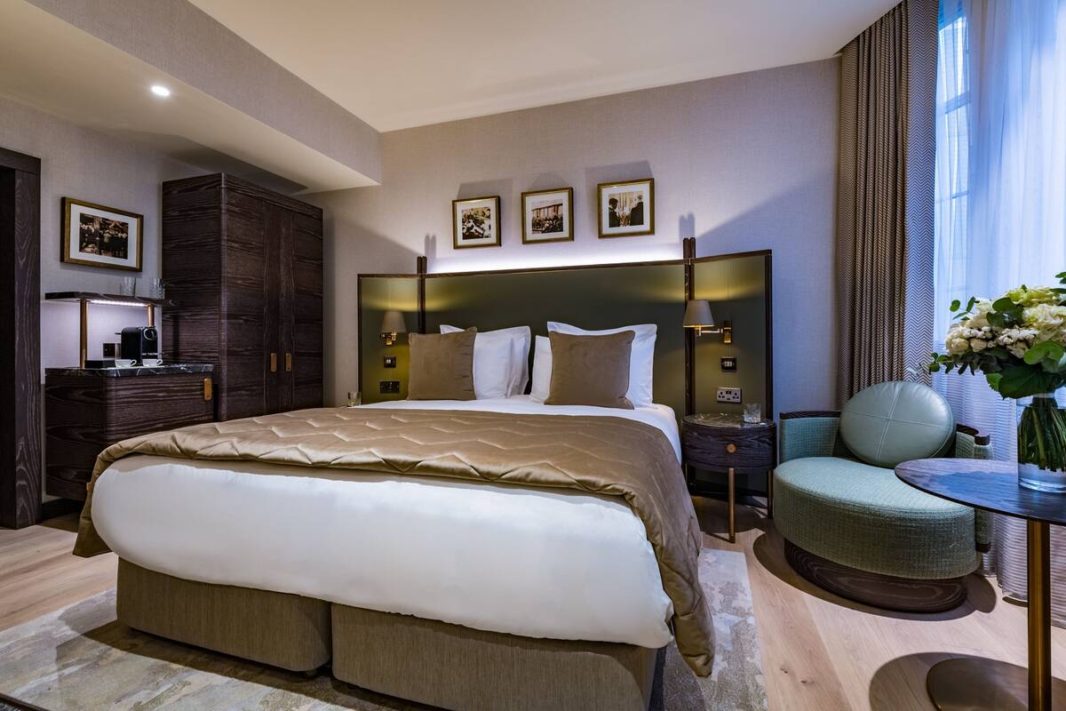 A modern hotel room with a large bed, a nightstand, a chair, and a desk.