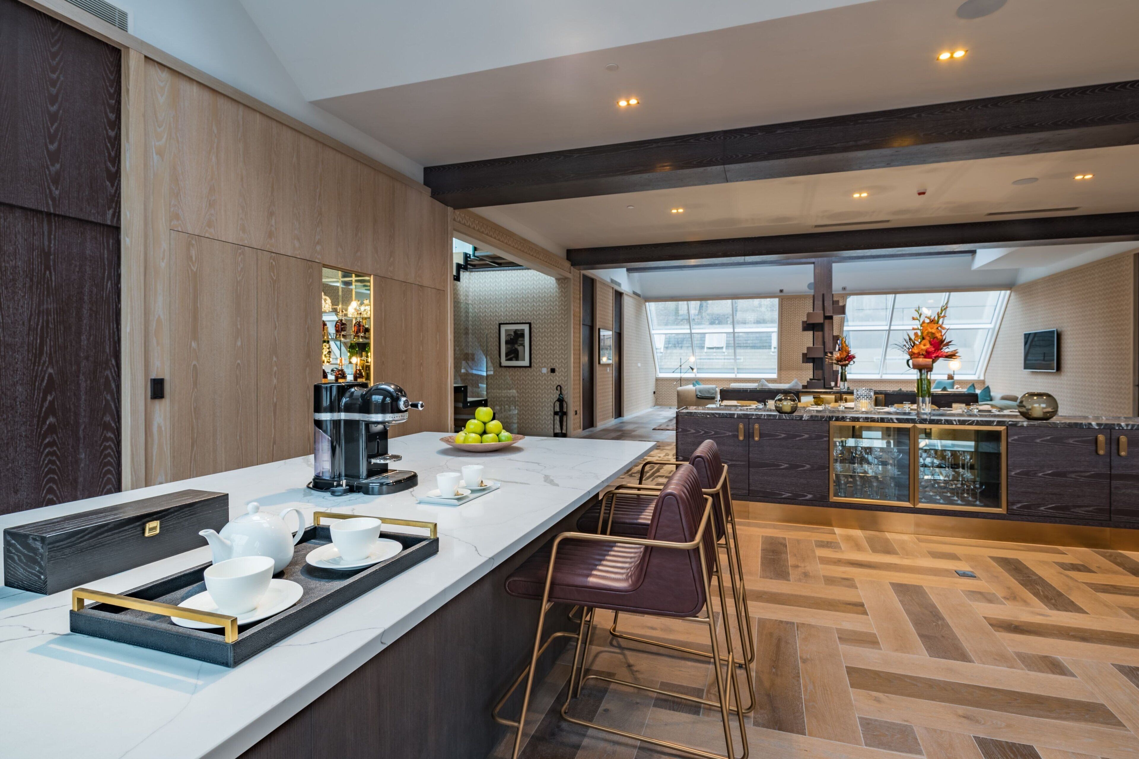 A modern kitchen with a large island, bar stools, and a view of the city through large windows.