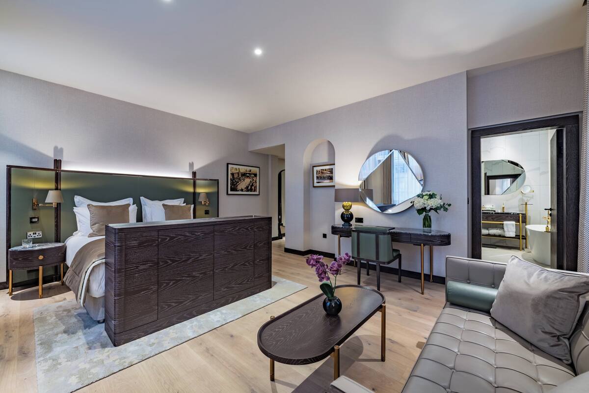 Una habitación de hotel moderna con una cama grande, un escritorio, un sofá y un comedor.