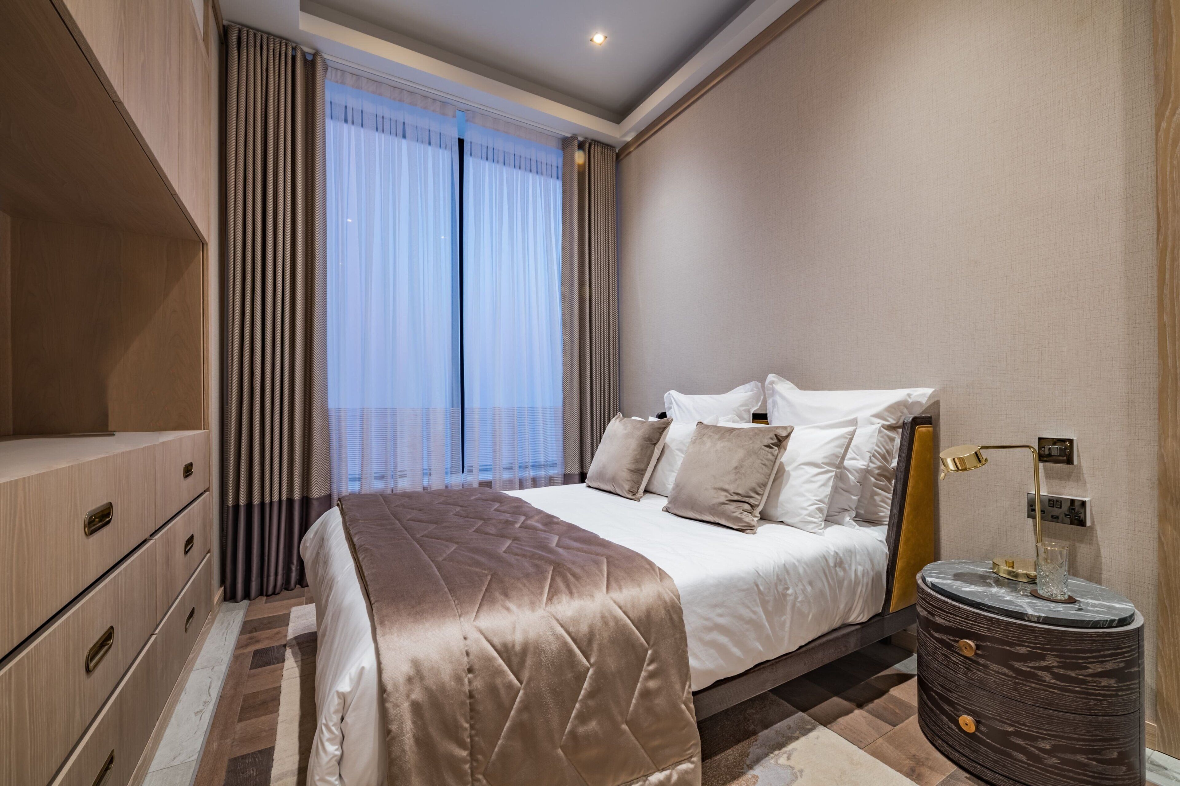 Une chambre moderne avec un grand lit, une table de chevet avec une lampe et une armoire.