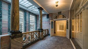 A grand hallway with marble columns, a patterned carpet, and a skylight.