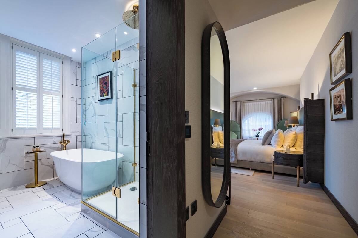 Un baño moderno con una bañera independiente, una ducha con mampara de vidrio y un espejo grande.