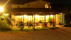 Una casa con un porche techado, plantas en macetas y mobiliario exterior.