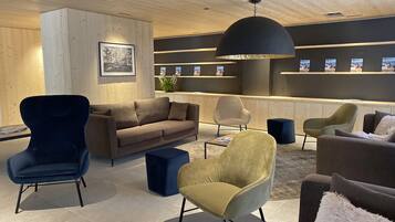A modern lounge area with a sofa, armchairs, and a coffee table.