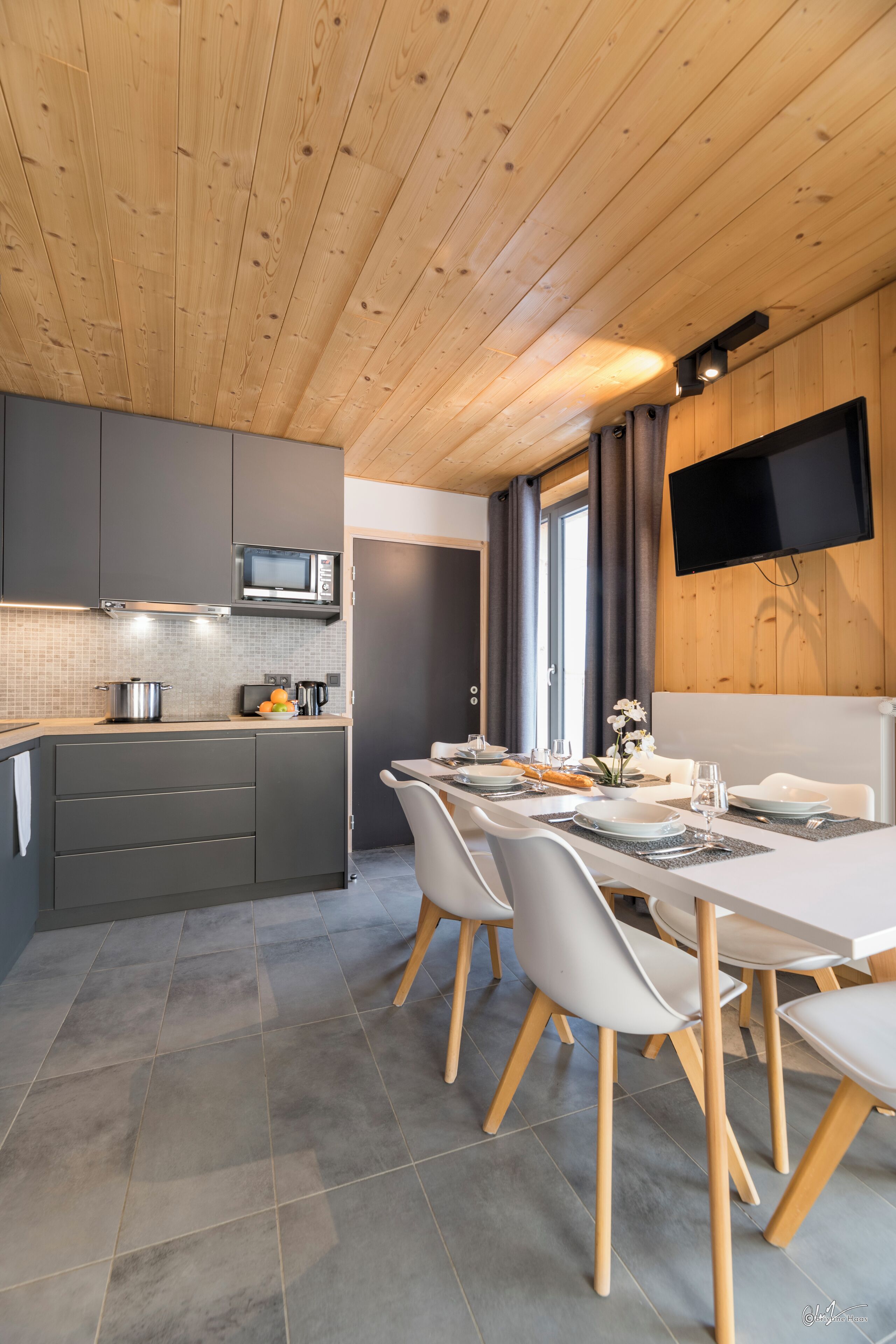 A modern kitchen with grey cabinets, a microwave, and a dining area with a white table and chairs.