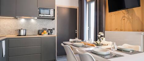 A modern kitchen with grey cabinets, a microwave, and a dining area with a white table and chairs.