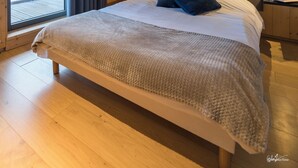 A bedroom with a wooden ceiling, a large bed with a white headboard, a mountain mural, and a view through a window with curtains. - Lagrange Vacances L'Ecrin du Badet (Aragnouet)