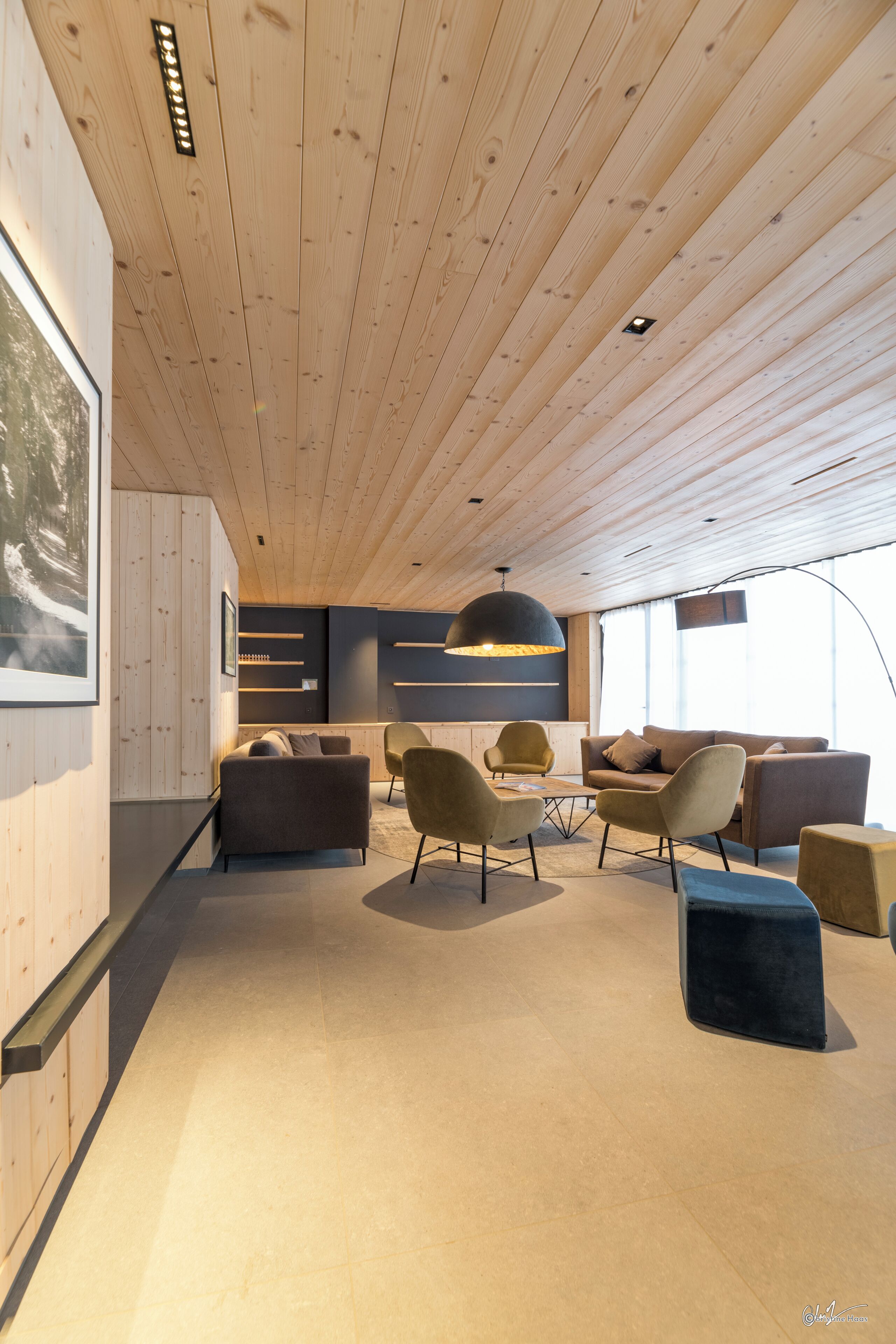 Et moderne interiør med træloft, en sofasæt og et spisebord.